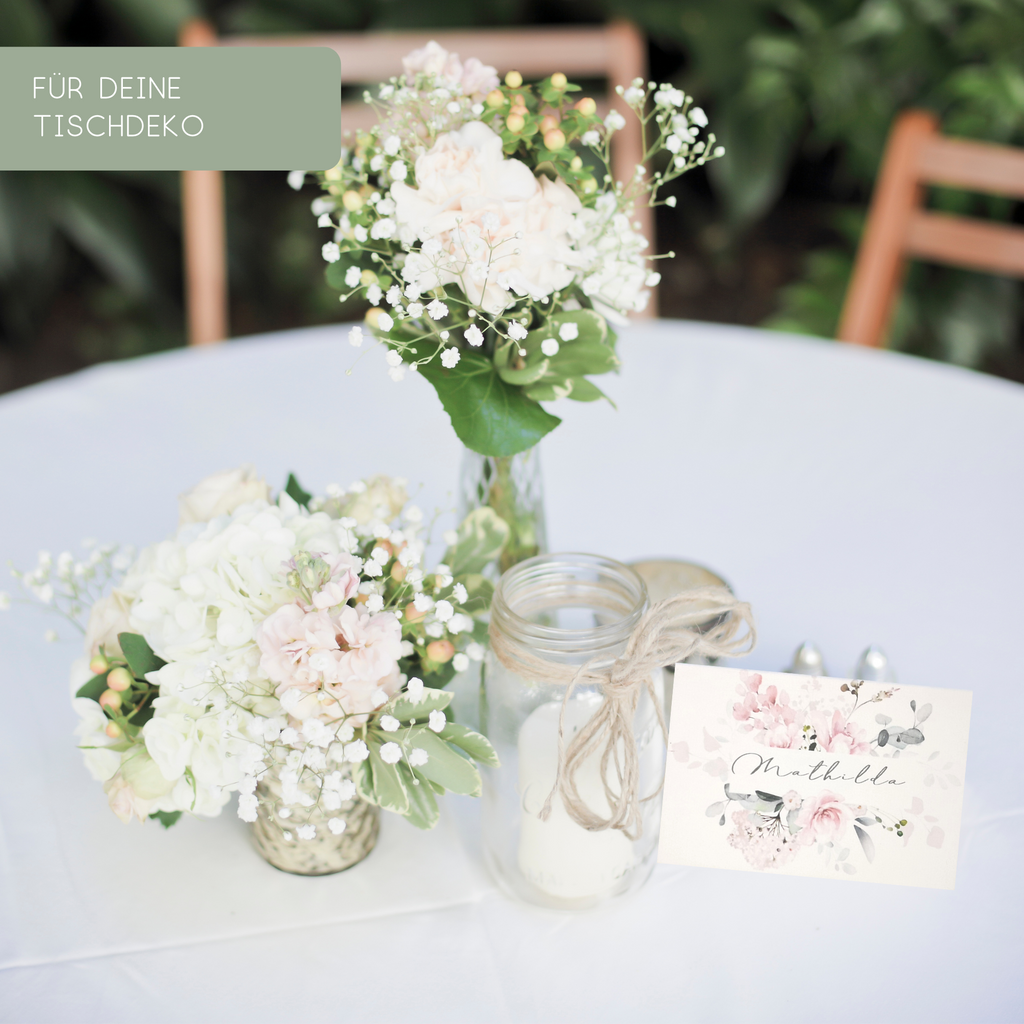 Geschmückter Tisch mit Blumen, Kerze und Namensschild